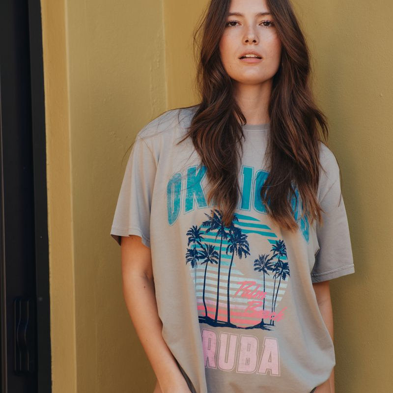 Woman wearing an okaicos t-shirt against a mustard yellow wall