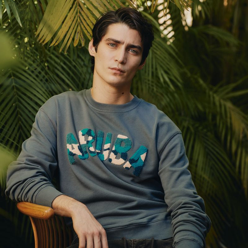 Man sitting in a chair with green foliage in the background