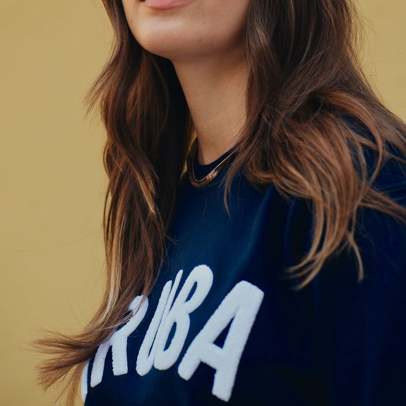 Woman wearing a bandana and a dark blue sweatshirt with 'Kuba' text on a beige background