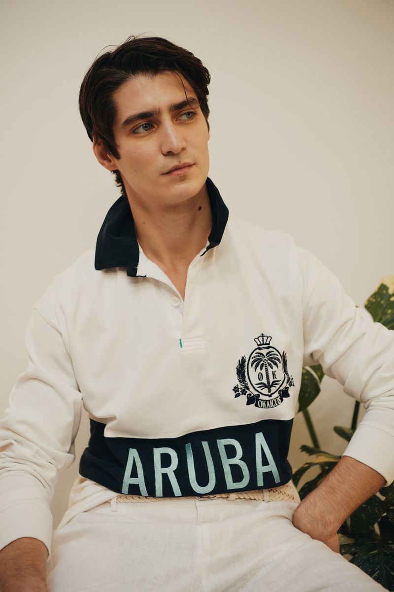 Man wearing a white polo shirt with 'ARUBA' branding, sitting against a neutral background.
