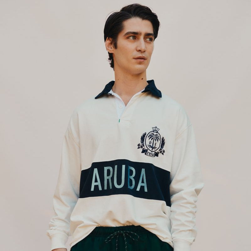Person wearing a white rugby shirt with 'ARUBA' text on a plain background