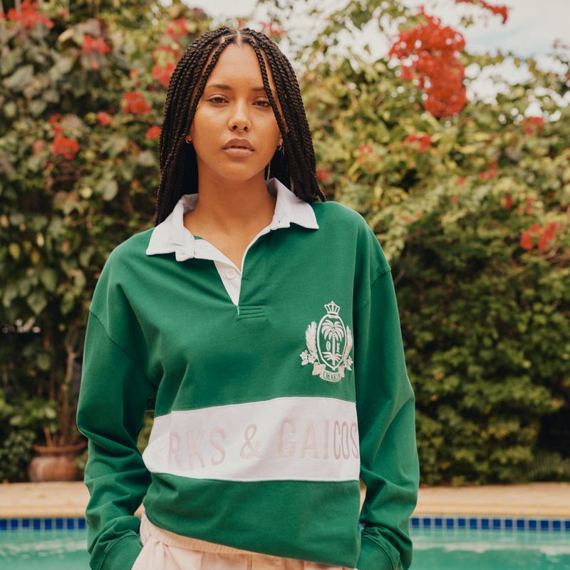 Person wearing a green and white sports jacket with a pool and garden in the background